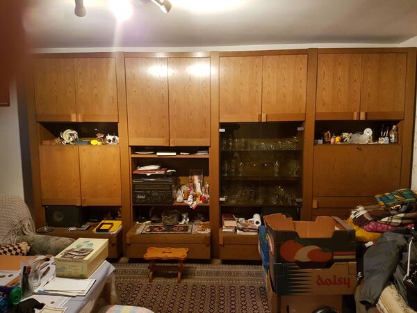 Großer Wohnzimmerschrank aus Holz mit Glastüren, Dekoration, Umzugskartons und Büchern.