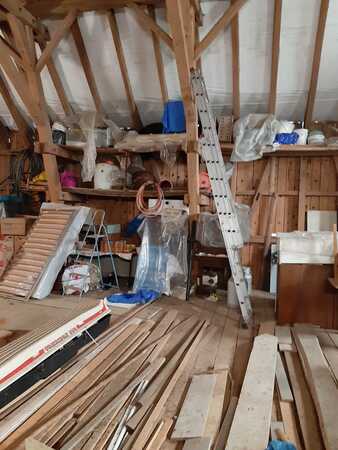 Dachboden mit Holzlatten, Bauwerkzeugen, Leiter und Baumaterialien für Renovierungsarbeiten.